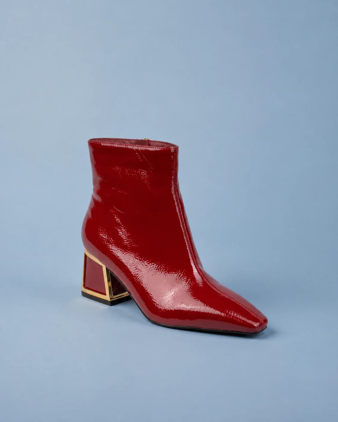 Brooke burgundy patent ankle boot on a powder blue studio backdrop